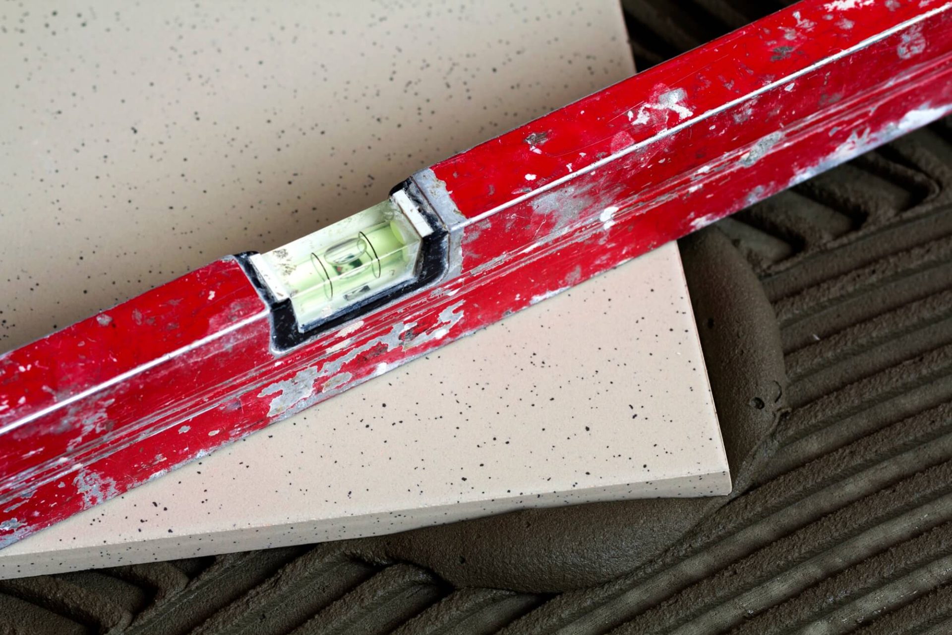 Hantverkare använder vattenpass för att säkerställa rak kakelsättning.